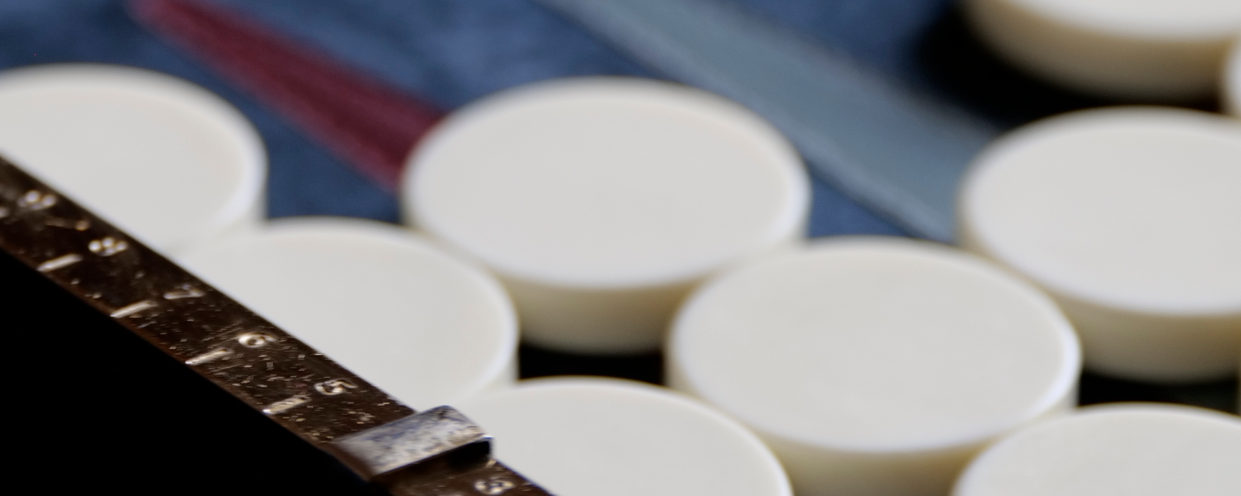 Close up of brass score counter on backgammon board with white checkers in background.